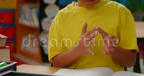 非裔美国小学生用手指在学校教室里的桌子旁数数的前景视频的预览图