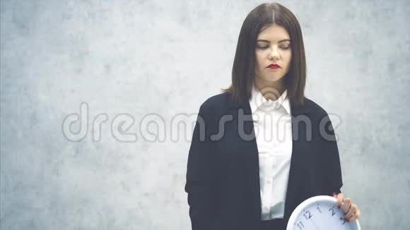 年轻疲惫的女商人穿着黑色西装看着时钟打着哈欠要睡觉了视频的预览图