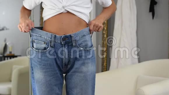 穿超大牛仔裤的苗条女孩穿大尺寸牛仔裤的女人很高兴她减肥了视频的预览图