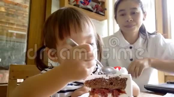 小亚洲女孩正在咖啡馆里给她妈妈喂蛋糕视频的预览图