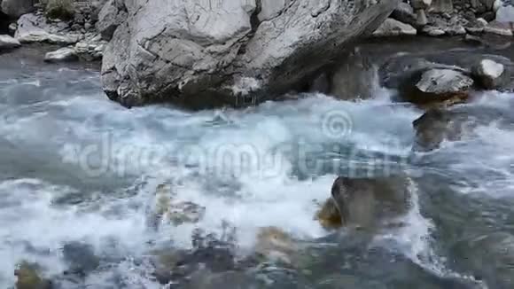 湍急的流水在一条山河里流淌秋天春天冬天的季节冰冻冰柱在岩石上视频的预览图