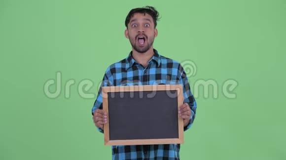 快乐的年轻留胡子的波斯时髦男人拿着黑板看上去很惊讶视频的预览图