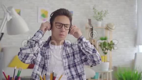 亚洲年轻人用耳机听充满活力的音乐视频的预览图