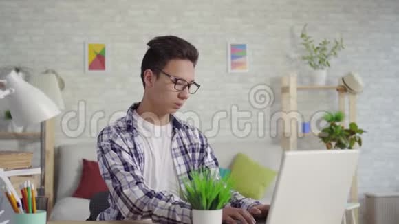 一个穿着衬衫的年轻人坐在笔记本电脑前心痛视频的预览图