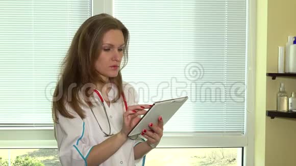 使用数字平板电脑对着窗户听诊器的女医生视频的预览图