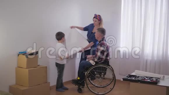 父亲坐轮椅的家庭在维修时在房间里愉快地选择新墙纸视频的预览图