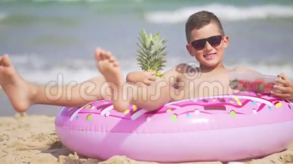 一个带着眼镜的男孩抱着菠萝躺在海底的充气圈上这就是视频的预览图