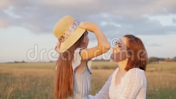 美丽的女人和她的女儿在湖边女孩穿上衣服摘下母亲帽子视频的预览图