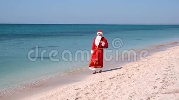 圣诞老人带着一袋礼物走在沙滩上青绿色的水视频的预览图