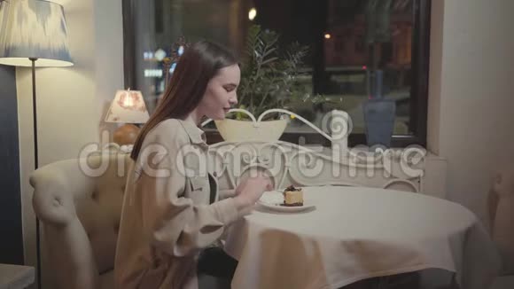 年轻漂亮的女孩在漂亮的餐厅里吃着新鲜令人垂涎的巧克力芝士蛋糕或提拉米苏视频的预览图