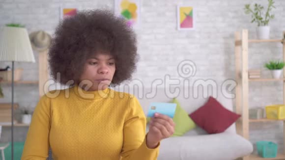 美国黑人妇女仔细认真地看着他手中的银行卡视频的预览图