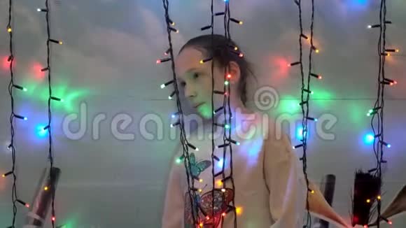 一个小女孩正站在房子的墙边玩圣诞灯她微笑着看着视频的预览图