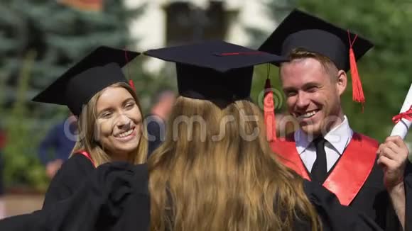 穿着学术服装的大学毕业生朋友互相祝贺视频的预览图