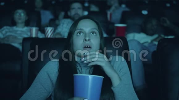 恐怖的女人在看恐怖电影时张口拿着爆米花视频的预览图