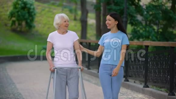 有爱心的年轻女子用步行架支持老太太社会志愿服务视频的预览图