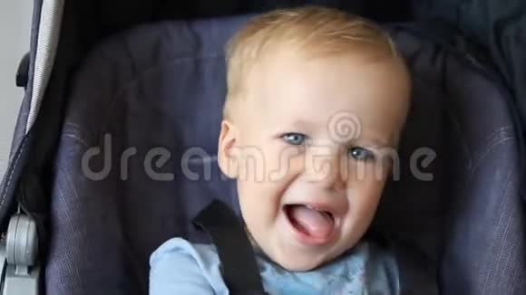 可爱可爱快乐的白种人金发幼儿男孩坐在婴儿车里笑着玩捉迷藏游戏有趣搞笑视频的预览图