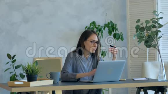 女性在室内刷卡购物白天使用笔记本视频的预览图
