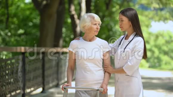 坐着步架的老年妇女和看镜头的女性治疗师视频的预览图