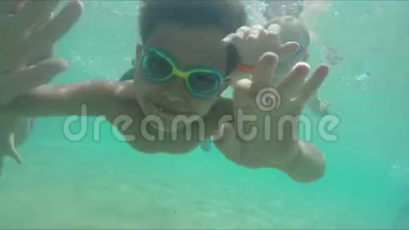 男孩和女孩游到水下摄像机前视频的预览图
