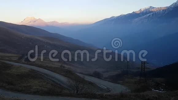 高加索山脉的日落日落时的山路蛇形和电力线视频的预览图