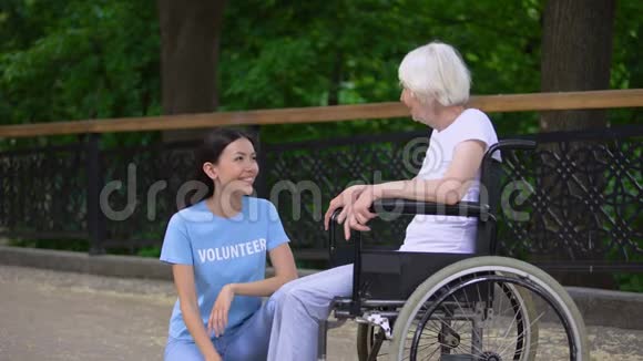 快乐志愿者听着老年妇女坐轮椅老人关心视频的预览图