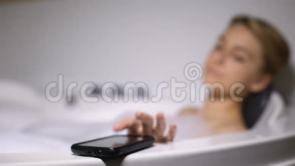 尴尬的年轻女人洗澡接电话把智能手机扔进水里视频的预览图