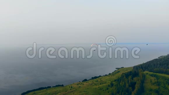 一个人用滑翔伞飞过绿色的小山空中滑翔伞视频的预览图