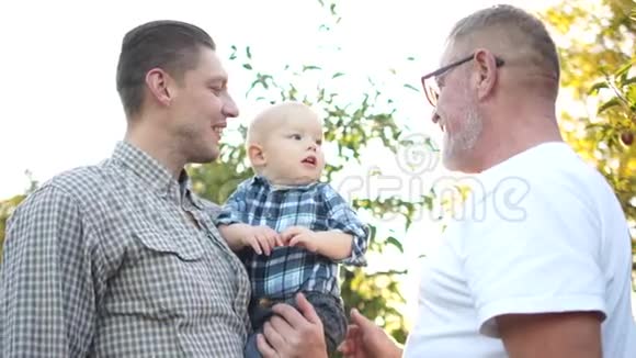 同一个家庭的三代人在日落时在苹果园玩得很开心祖父儿子和孙子笑视频的预览图