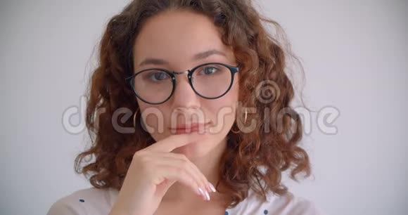 戴眼镜的白种人年轻漂亮长头发卷曲的女性的特写镜头笑着开心地看着镜头视频的预览图