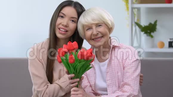 抱着祖母和孙女捧着一束郁金香看着镜头视频的预览图