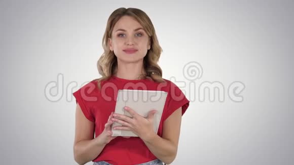 主持人女士穿着红色t恤拿着平板电脑翻页在渐变背景下与相机交谈视频的预览图