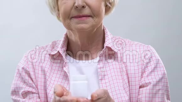 一位老妇人在镜头前拿出一罐有愈合膏的罐子药物生产视频的预览图