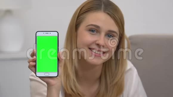 漂亮的女孩展示智能手机和绿色屏幕广告移动网站视频的预览图