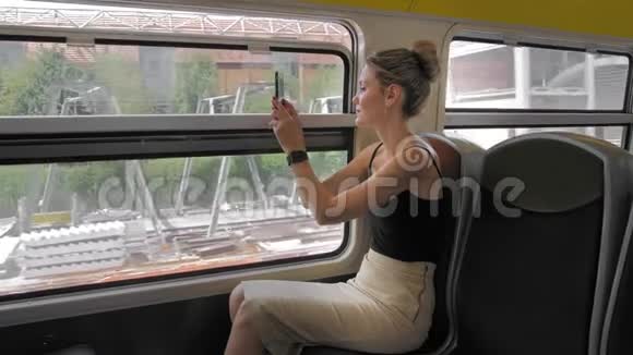 美丽的高加索女性游客乘坐火车拍摄城市工业区的照片在窗户里视频的预览图