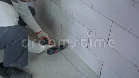 建筑工人用电钻在砌块墙上凿孔时倾斜视频的预览图