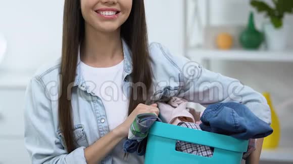 微笑的年轻女子拿着篮子脏衣服洗衣服务特写视频的预览图