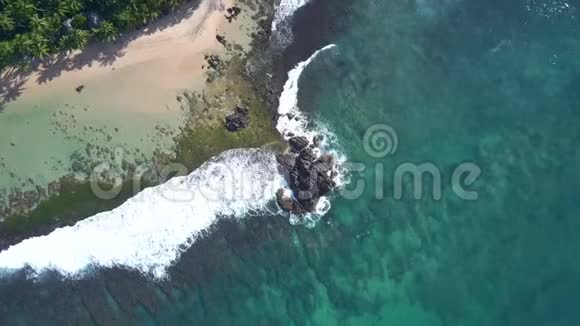 在绿色沙滩海岸线上的海浪之间的悬崖视频的预览图
