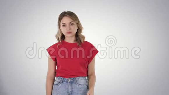 年轻的女人一头金发穿着红色T恤在渐变的背景看着镜头毫无感情视频的预览图