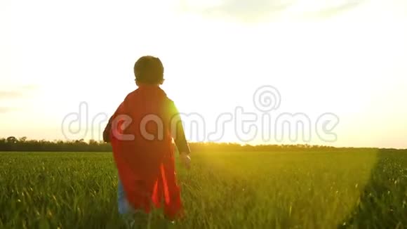 一个打扮成超级英雄的孩子穿过绿草走向日落视频的预览图
