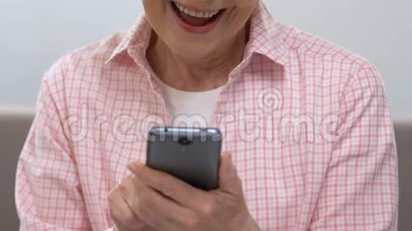 快乐的老妇人在智能手机上滚动看家庭照片特写视频的预览图