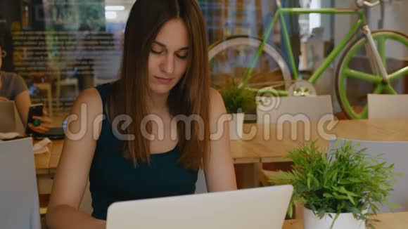 年轻漂亮的女人在一个现代的同事办公室的笔记本电脑工作视频的预览图