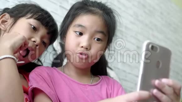 亚洲儿童女孩在客厅用智能手机自拍视频的预览图