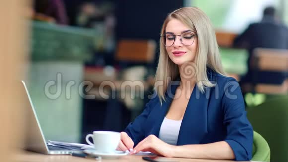 微笑的女商人的肖像戴着时髦的眼镜在咖啡馆里摆姿势看镜头视频的预览图