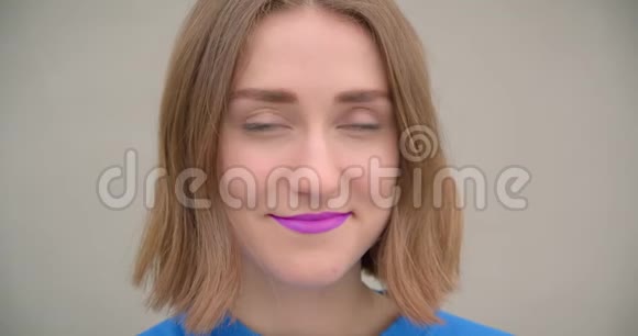 一位年轻的黑发女性涂着紫色口红兴高采烈地摆在面前的特写肖像视频的预览图