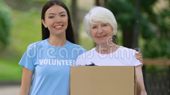 志愿者抱着老妇人拿着盒子带着衣服社会支持捐款视频的预览图