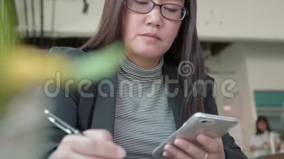 女人在游泳池里用手机短信女人在餐馆里用智能手机写笔记视频的预览图