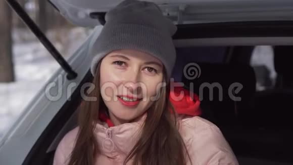 一个美丽的女孩坐在冬天的森林里的车里翻过日记视频的预览图