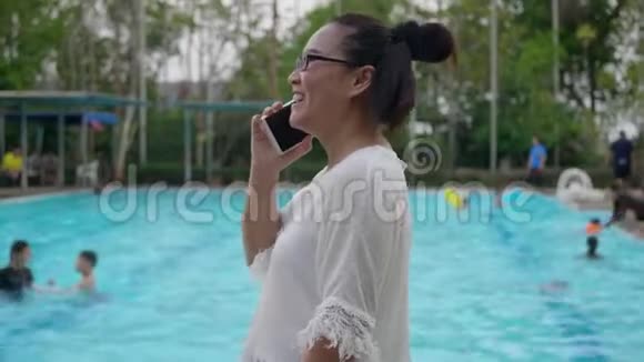 在游泳池附近用手机的女人视频的预览图
