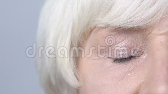 退休妇女闭上疲惫的眼睛泪珠顺着脸颊流下泪珠视频的预览图