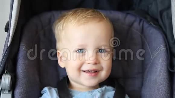 可爱可爱快乐的白种人金发幼儿男孩坐在婴儿车里笑着玩捉迷藏游戏有趣搞笑视频的预览图